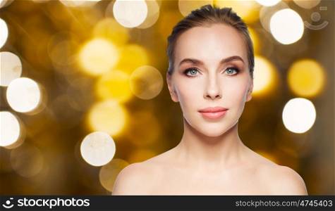 beauty, people and holidays concept - beautiful young woman face over lights background