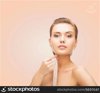 beauty, people and jewelry concept - beautiful woman with pearl earrings and necklace over beige background