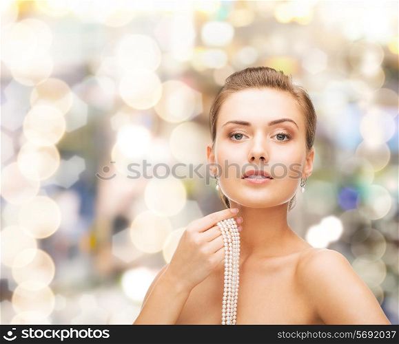 beauty, people and jewelry concept - beautiful woman with pearl earrings and necklace over lights background