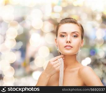 beauty, people and jewelry concept - beautiful woman with pearl earrings and necklace over lights background