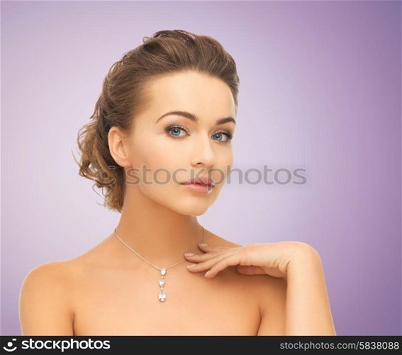 beauty, people and jewelry concept - beautiful young woman wearing shiny diamond pendant over violet background