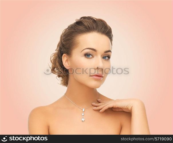 beauty, people and jewelry concept - woman wearing shiny diamond pendant over pink background