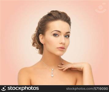 beauty, people and jewelry concept - woman wearing shiny diamond pendant over pink background