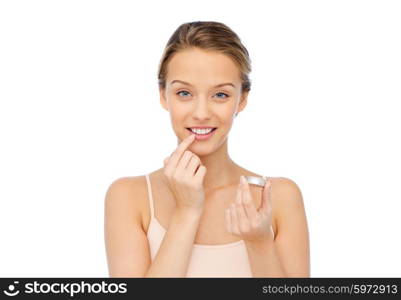 beauty, people and lip care concept - smiling young woman applying lip balm to her lips