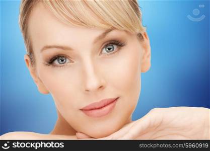 beauty, people and makeover concept - beautiful young woman face over blue background