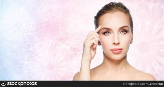 beauty, people and plastic surgery concept - beautiful young woman pointing finger at her forehead over pink patterned background