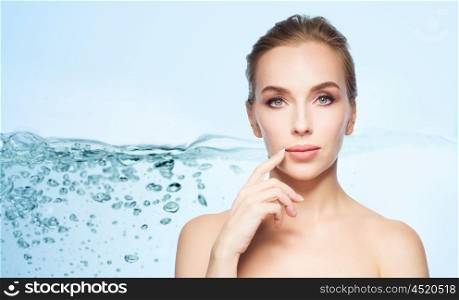 beauty, people and plastic surgery concept - beautiful young woman showing her lips over water splash bubbles on blue background