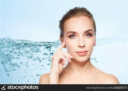 beauty, people and plastic surgery concept - beautiful young woman showing her cheekbone over blue background with water splash. beautiful young woman showing her cheekbone