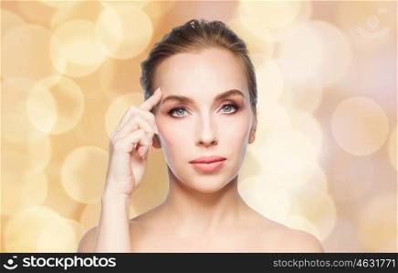 beauty, people and plastic surgery concept - beautiful young woman showing her forehead over holidays lights background