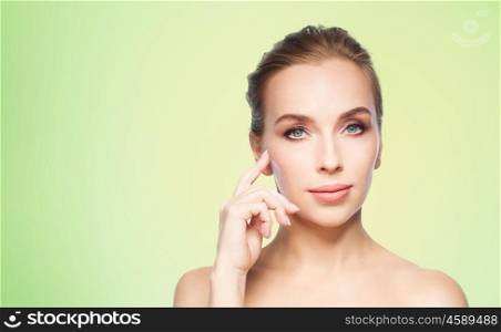 beauty, people and plastic surgery concept - beautiful young woman showing her cheekbone over green background