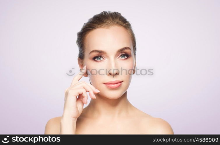 beauty, people and plastic surgery concept - beautiful young woman showing her cheekbone over violet background