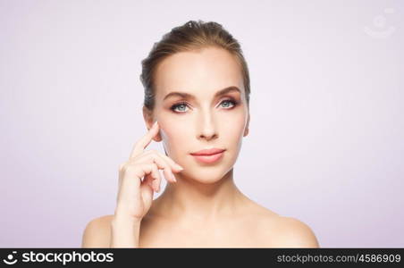 beauty, people and plastic surgery concept - beautiful young woman showing her cheekbone over violet background