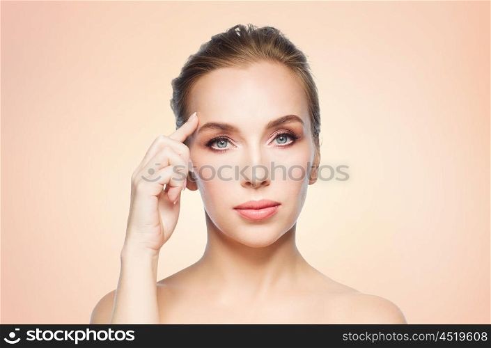 beauty, people and plastic surgery concept - beautiful young woman showing her forehead over beige background