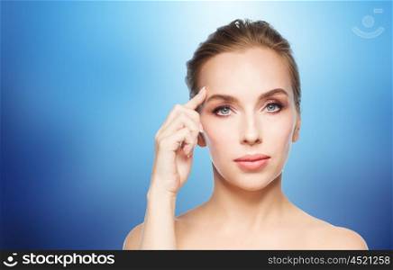 beauty, people and plastic surgery concept - beautiful young woman showing her forehead over blue background