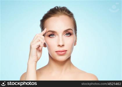 beauty, people and plastic surgery concept - beautiful young woman showing her forehead over blue background