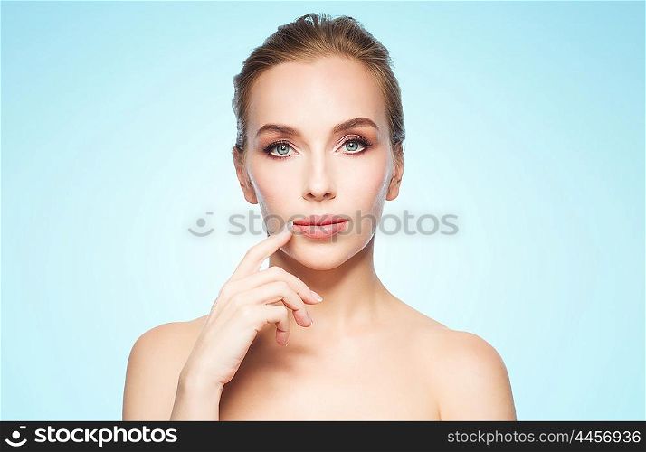 beauty, people and plastic surgery concept - beautiful young woman showing her lips over blue background