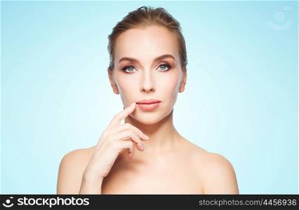 beauty, people and plastic surgery concept - beautiful young woman showing her lips over blue background