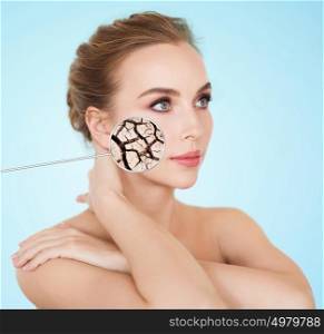 beauty, people and skin care concept - beautiful young woman face with dehydrated cracked dry skin over blue background. woman face with dehydrated cracked dry skin
