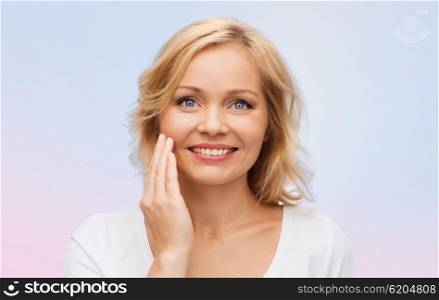 beauty, people and skincare concept - smiling woman in white shirt touching face over rose quartz and serenity gradient background