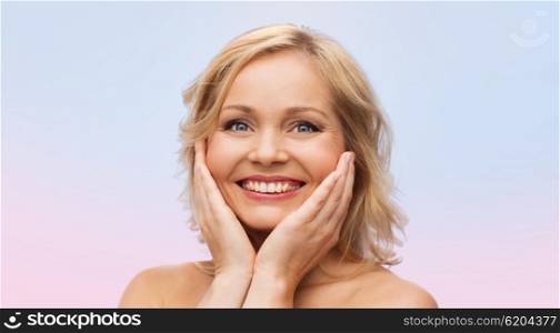 beauty, people and skincare concept - smiling woman with bare shoulders touching face over rose quartz and serenity gradient background