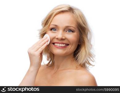 beauty, people and skincare concept - young woman cleaning face and removing make up with cotton pad