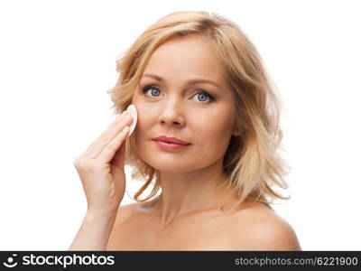 beauty, people and skincare concept - young woman cleaning face and removing make up with cotton pad