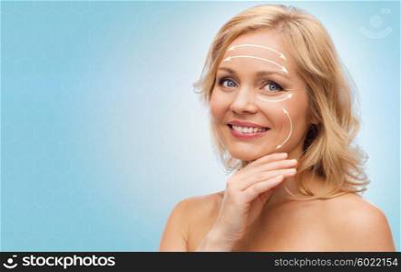 beauty, people, anti-aging and skincare concept - smiling woman with bare shoulders touching face over blue background