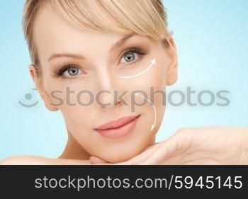 beauty, people, anti-aging treatment and plastic surgery concept - beautiful young woman with face lifting arrows over blue background