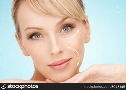beauty, people, anti-aging treatment and plastic surgery concept - beautiful young woman with face lifting arrows over blue background