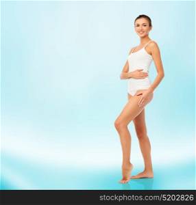 beauty, people, anticellulite and bodycare concept - beautiful young woman in white underwear over blue background. beautiful young woman in white underwear
