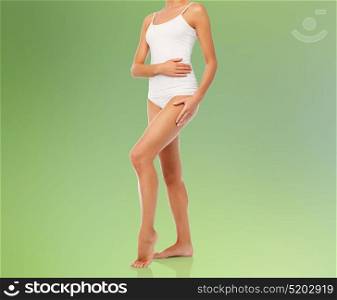 beauty, people, anticellulite and bodycare concept - body of beautiful young woman in white underwear over green natural background. body of beautiful young woman in white underwear