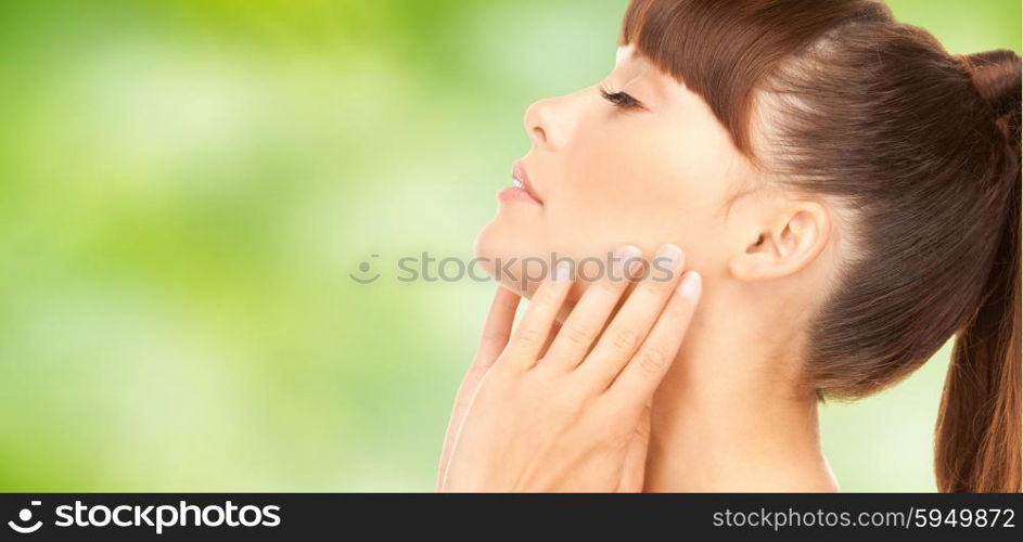 beauty, people, body care and health concept - beautiful young woman face over green natural background