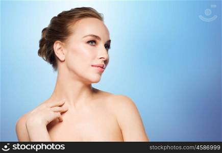 beauty, people, bodycare and health concept - beautiful young woman touching her neck over blue background