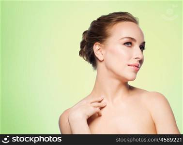 beauty, people, bodycare and health concept - beautiful young woman touching her neck over green background