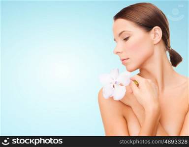 beauty, people, bodycare and health concept - beautiful young woman with orchid flower and bare shoulders over blue background