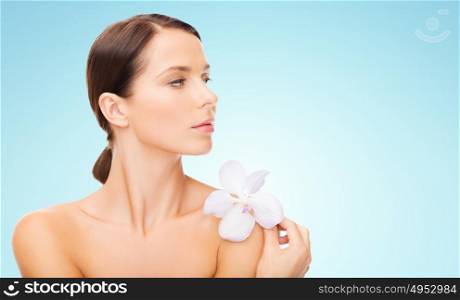 beauty, people, bodycare and health concept - beautiful young woman with orchid flower and bare shoulders over blue background. beautiful young woman with orchid flower