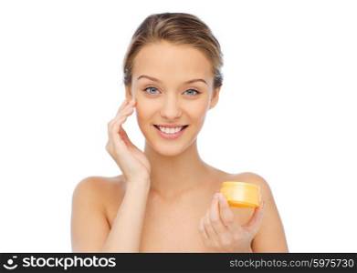 beauty, people, cosmetics, skincare and cosmetics concept - happy young woman appying cream to her face