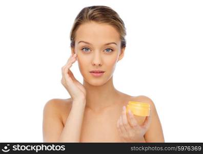 beauty, people, cosmetics, skincare and cosmetics concept - young woman appying cream to her face