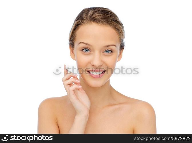 beauty, people, cosmetics, skincare and health concept - happy smiling young woman applying cream to her face