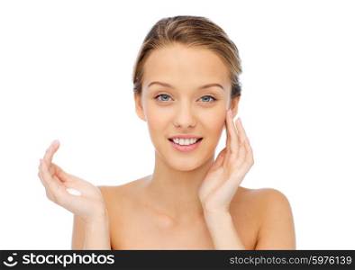 beauty, people, cosmetics, skincare and health concept - happy smiling young woman applying cream to her face