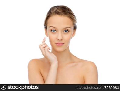 beauty, people, cosmetics, skincare and health concept - young woman applying cream to her face