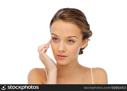 beauty, people, cosmetics, skincare and health concept - young woman applying cream to her face