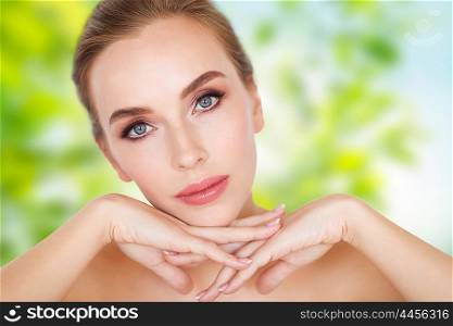 beauty, people, eco and bodycare concept -beautiful young woman face and hands over green natural background