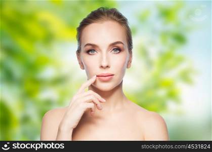 beauty, people, eco and plastic surgery concept - beautiful young woman showing her lips over green natural background