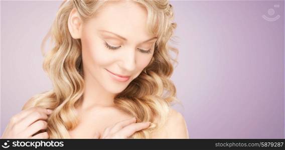 beauty, people, hair care and health concept - beautiful young woman face with long wavy hair over violet background