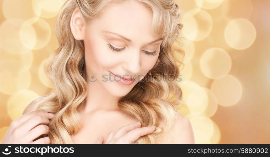 beauty, people, hair care and health concept - beautiful young woman face with long wavy hair over beige lights background