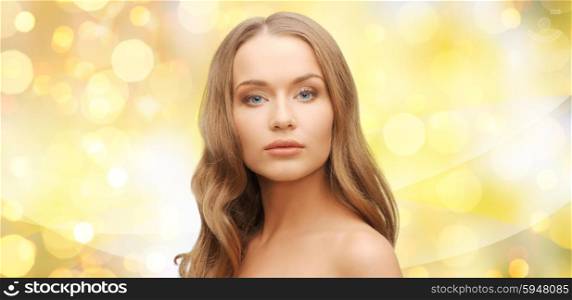 beauty, people, hair care, holidays and health concept - beautiful young woman face over yellow lights background