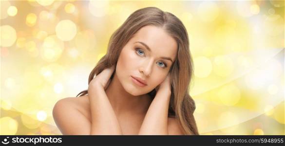 beauty, people, hair care, holidays and health concept - beautiful young woman face over yellow lights background