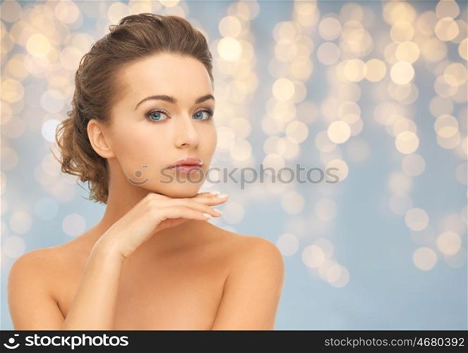 beauty, people, holidays and skin care concept - beautiful young woman face and hands over lights background