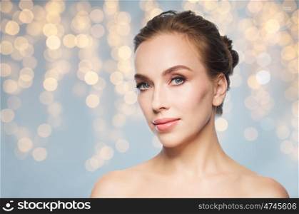 beauty, people, holidays and skin care concept - beautiful young woman face over lights background